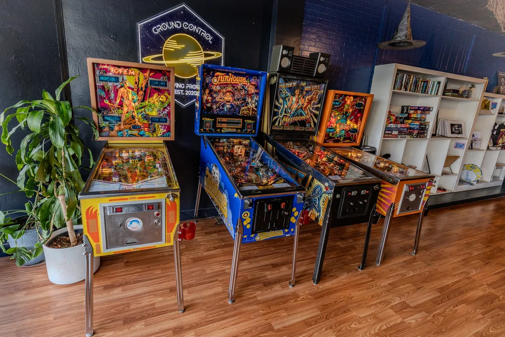 A row of pinball machines under the Ground Control neon sign